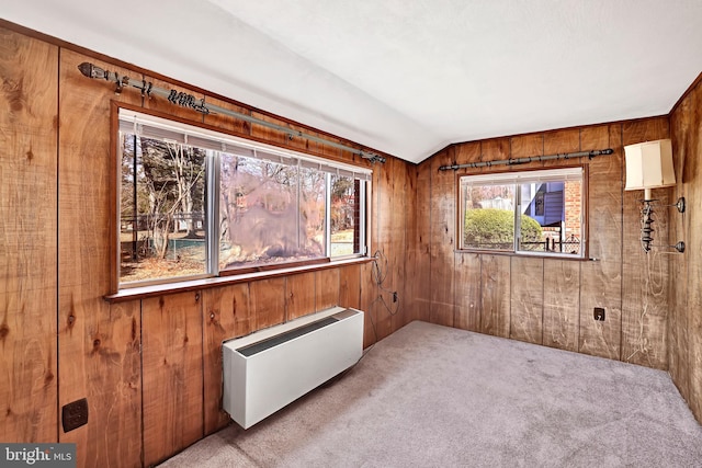 empty room with lofted ceiling, carpet flooring, and wood walls