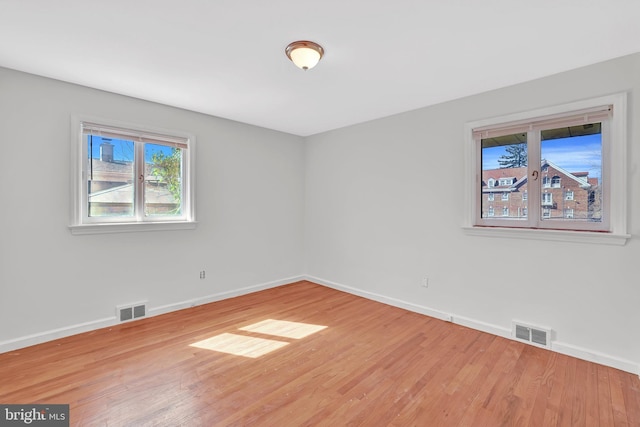 empty room with visible vents, baseboards, and wood finished floors