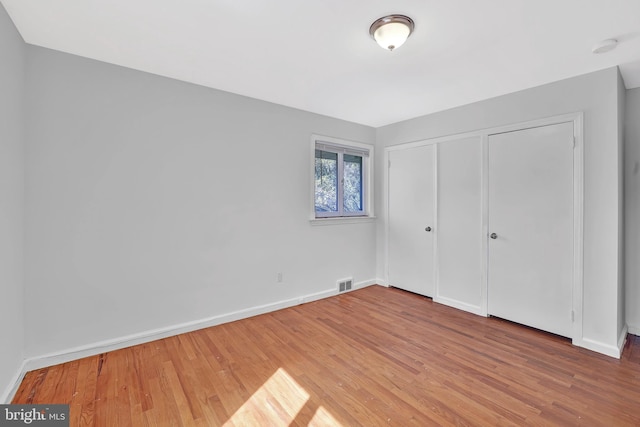 unfurnished bedroom featuring visible vents, baseboards, and wood finished floors