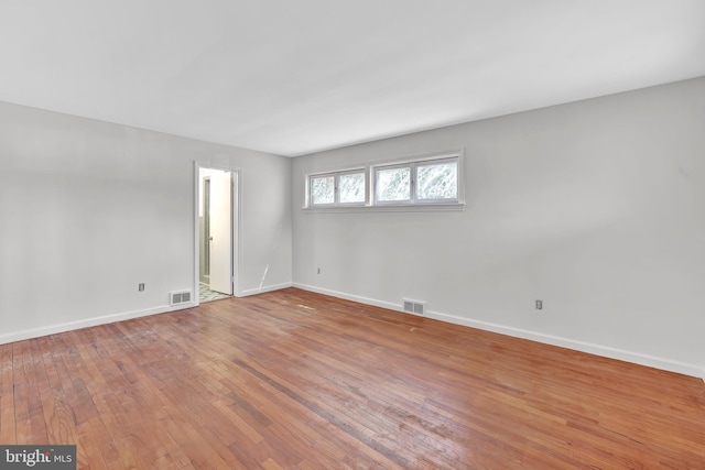 empty room featuring visible vents, wood-type flooring, and baseboards