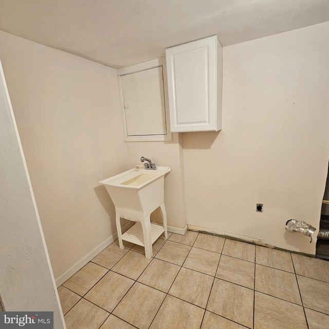 clothes washing area with light tile patterned floors, cabinet space, electric dryer hookup, and baseboards