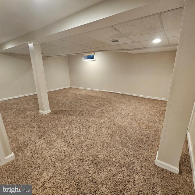 finished below grade area with carpet flooring, a paneled ceiling, and baseboards