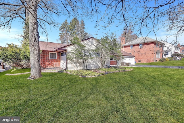 exterior space featuring a front lawn, an attached garage, brick siding, and driveway