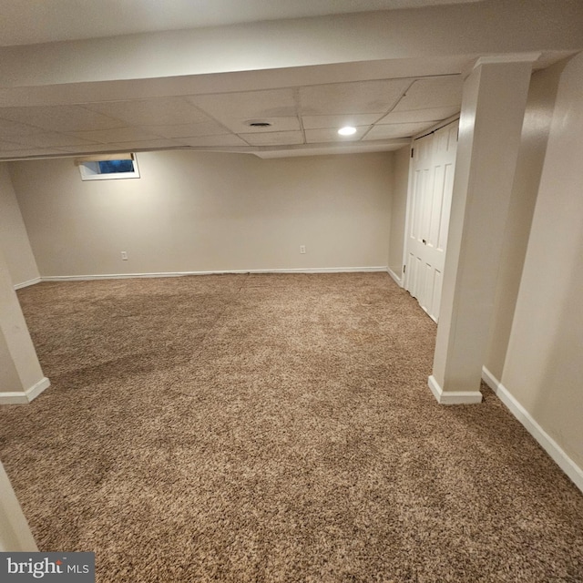 finished basement featuring a drop ceiling, baseboards, and carpet