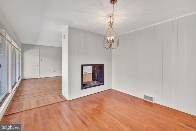 interior space with a wealth of natural light, visible vents, a notable chandelier, and wood finished floors