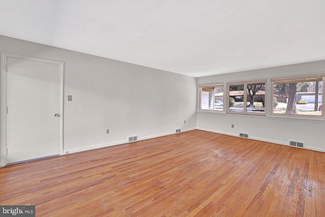 spare room featuring visible vents, baseboards, and light wood-style floors