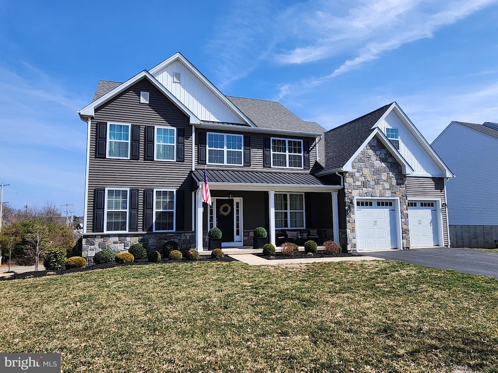 view of front of house featuring aphalt driveway, stone siding, an attached garage, and a front lawn