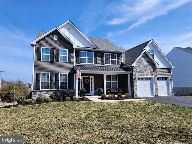 view of front of house featuring aphalt driveway, stone siding, an attached garage, and a front lawn