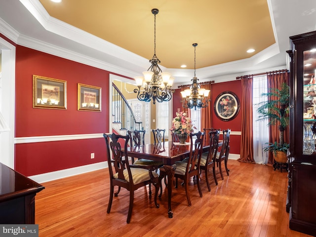 dining space with light wood finished floors, an inviting chandelier, baseboards, and a tray ceiling