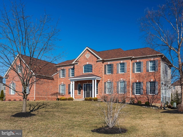 colonial home with a front lawn and brick siding