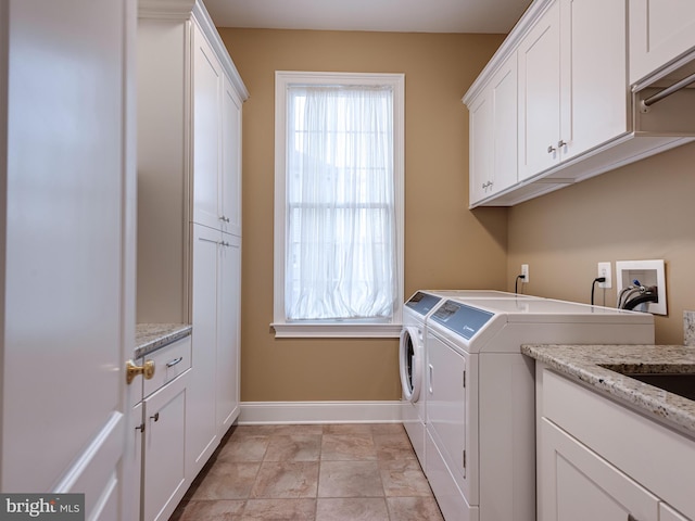 laundry area featuring cabinet space, plenty of natural light, washing machine and dryer, and baseboards