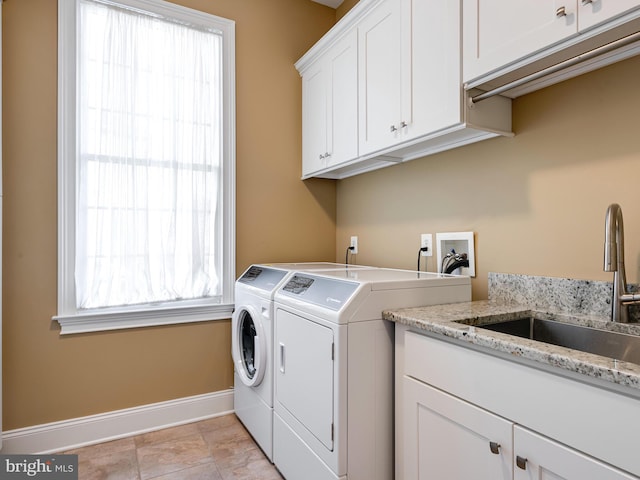 laundry room with cabinet space, washer and dryer, baseboards, and a sink