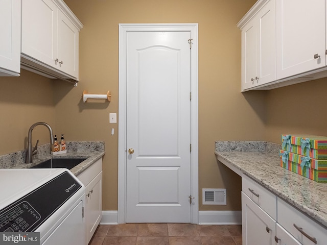 washroom with visible vents, a sink, cabinet space, light tile patterned flooring, and baseboards