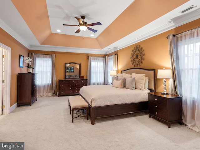 bedroom with a raised ceiling, multiple windows, and visible vents