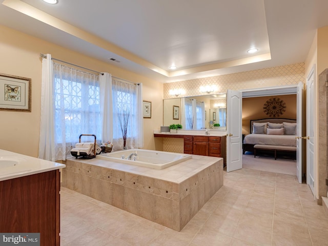 full bathroom with visible vents, vanity, a raised ceiling, and a garden tub