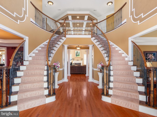 entryway featuring stairway, wood finished floors, baseboards, decorative columns, and crown molding