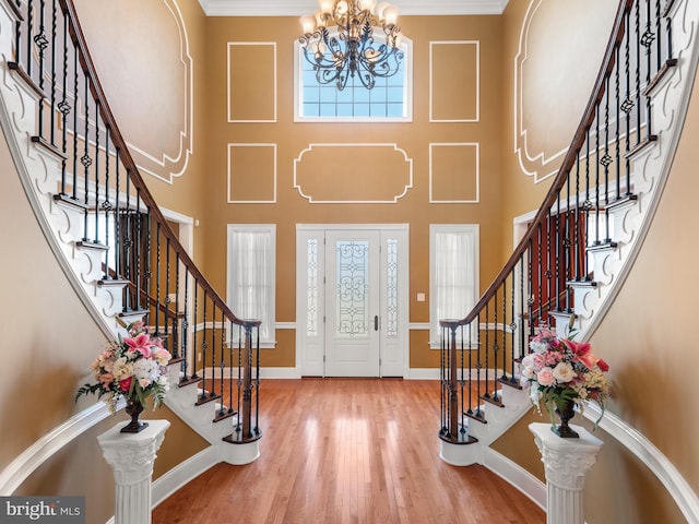 entrance foyer featuring stairs, an inviting chandelier, wood finished floors, and baseboards