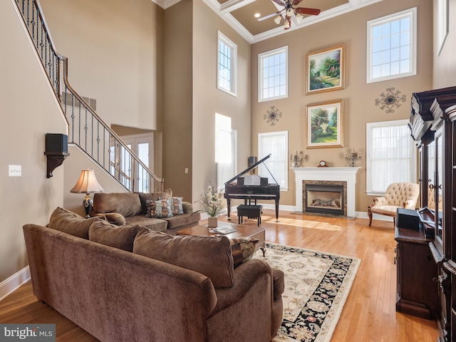 living area with ceiling fan, baseboards, crown molding, and light wood-style floors