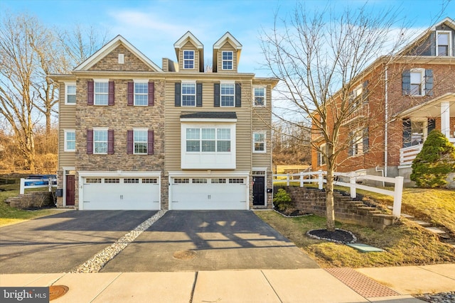 multi unit property with stone siding, driveway, an attached garage, and fence