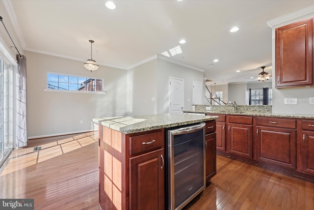 kitchen featuring wine cooler, ornamental molding, dark wood-style flooring, and a kitchen island