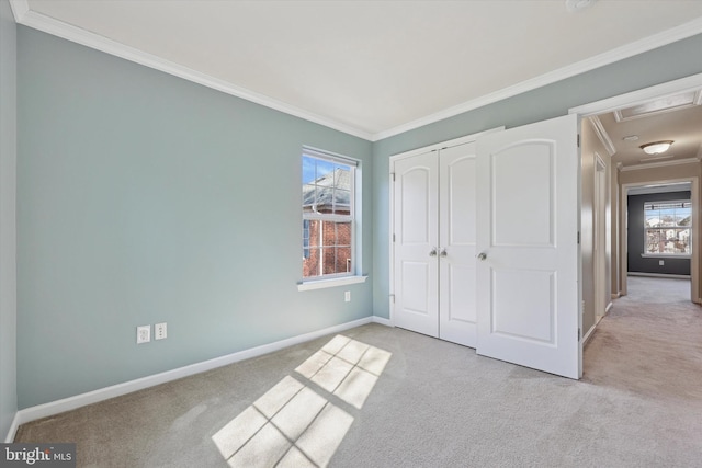 unfurnished bedroom with crown molding, carpet, baseboards, and a closet