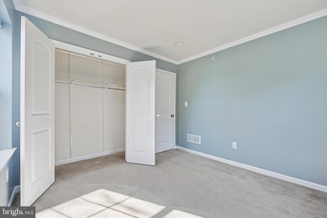 unfurnished bedroom with visible vents, ornamental molding, a closet, carpet, and baseboards