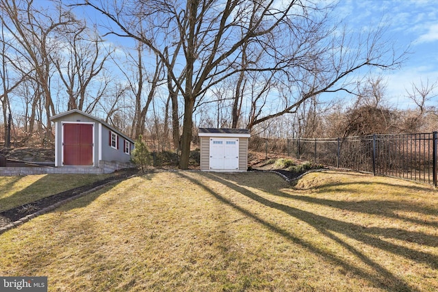 view of yard featuring an outbuilding, a storage shed, and fence