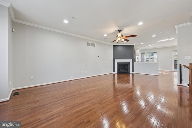 unfurnished living room featuring visible vents, ornamental molding, a glass covered fireplace, and wood-type flooring