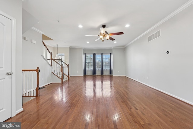 unfurnished living room with hardwood / wood-style floors, stairway, baseboards, visible vents, and crown molding