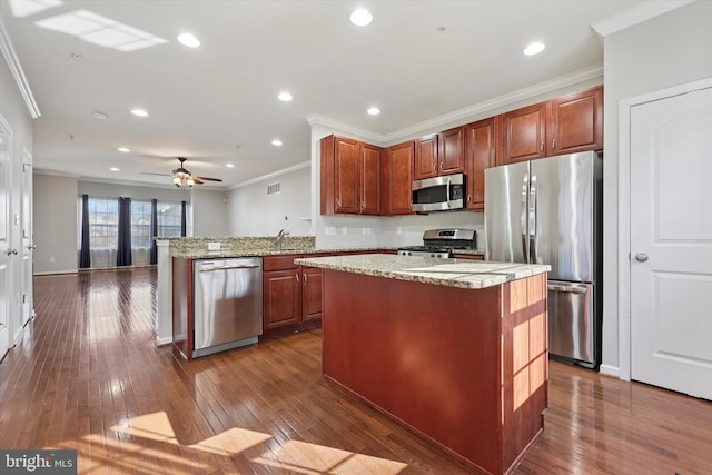 kitchen with a peninsula, crown molding, dark wood-type flooring, and appliances with stainless steel finishes