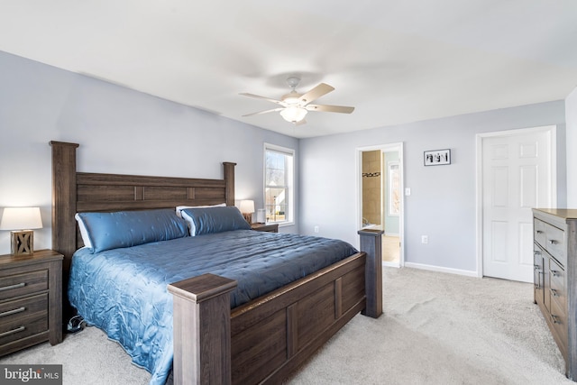 bedroom featuring light colored carpet, ensuite bath, baseboards, and a ceiling fan