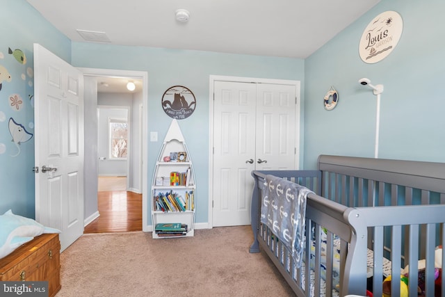 carpeted bedroom featuring a closet, baseboards, and a crib