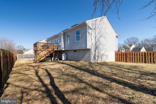 rear view of house featuring a lawn, a wooden deck, stairs, and a fenced backyard