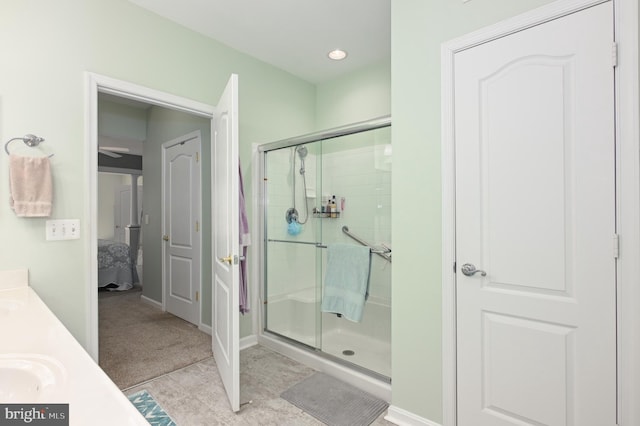 full bathroom with double vanity, baseboards, a stall shower, and ensuite bathroom