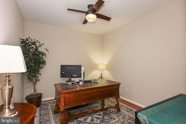 office space with baseboards and ceiling fan