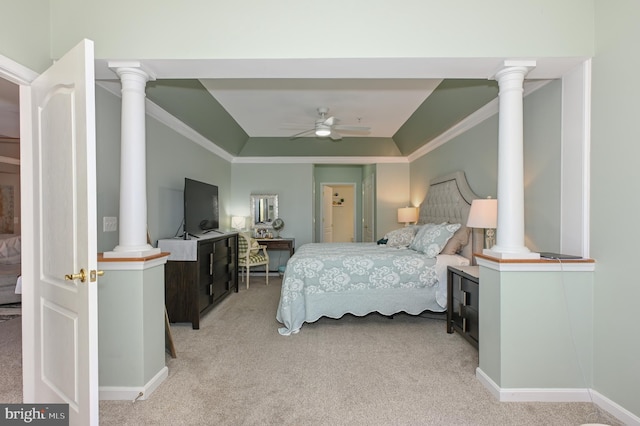 bedroom with a tray ceiling, decorative columns, light carpet, and crown molding