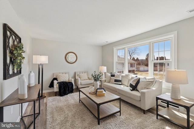 living room with visible vents, baseboards, and light wood finished floors