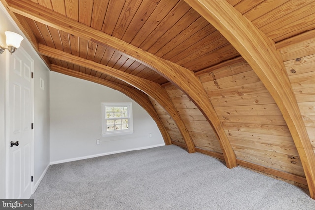 additional living space featuring baseboards, vaulted ceiling with beams, wood ceiling, and carpet