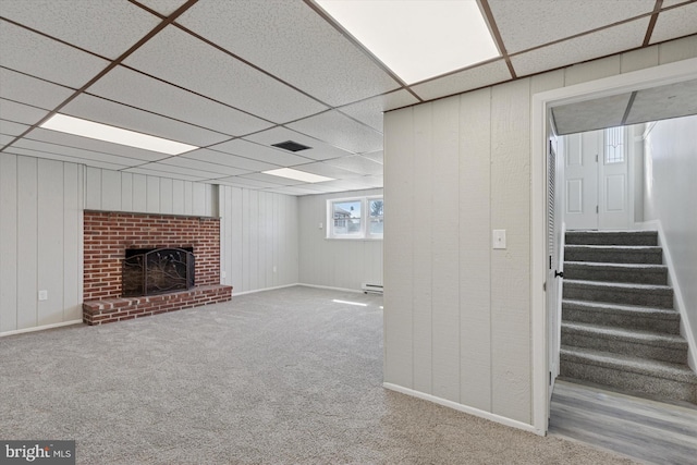 basement featuring stairway, visible vents, carpet floors, a fireplace, and a paneled ceiling