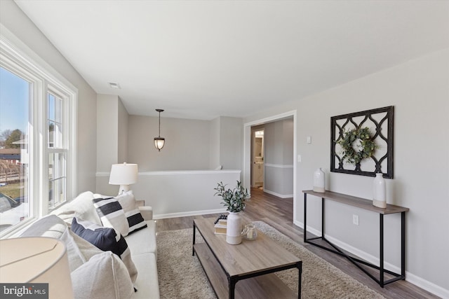 living area featuring visible vents, baseboards, and wood finished floors