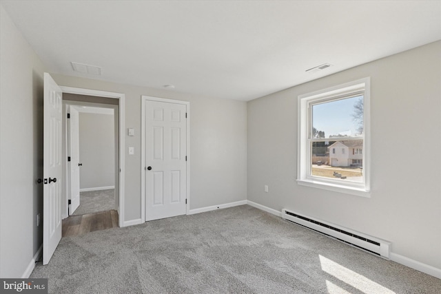 unfurnished bedroom featuring baseboards, a baseboard heating unit, carpet floors, and visible vents