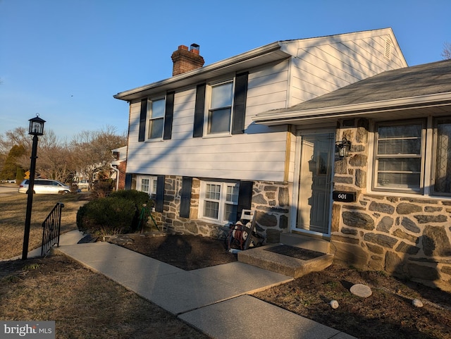 view of front of property featuring stone siding and a chimney