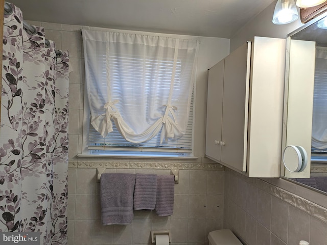 full bath featuring a shower with curtain, tile walls, and toilet