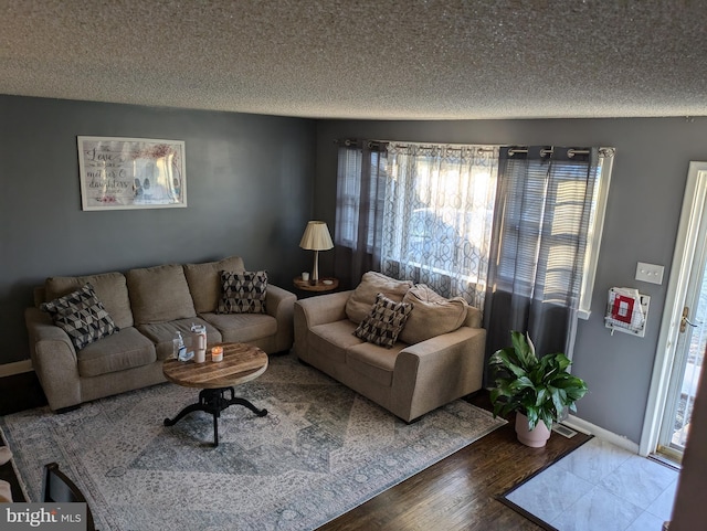 living area featuring a textured ceiling, baseboards, and wood finished floors