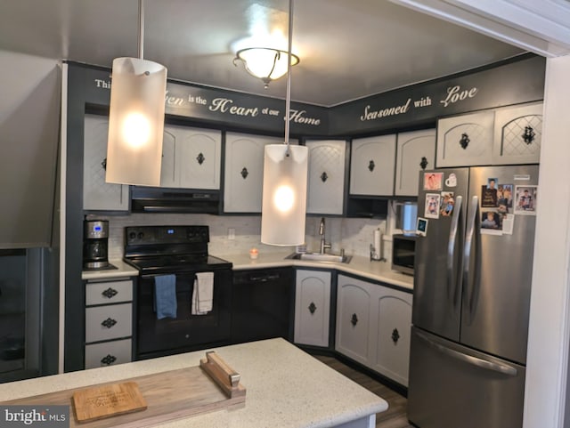 kitchen featuring tasteful backsplash, ventilation hood, light countertops, black appliances, and a sink