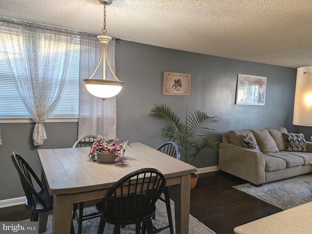 dining area with dark wood-style floors, baseboards, and a textured ceiling