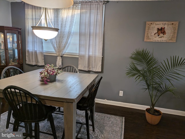 dining space featuring wood finished floors and baseboards