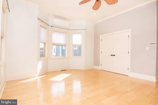 unfurnished room featuring visible vents, crown molding, baseboards, a wall unit AC, and light wood-style floors