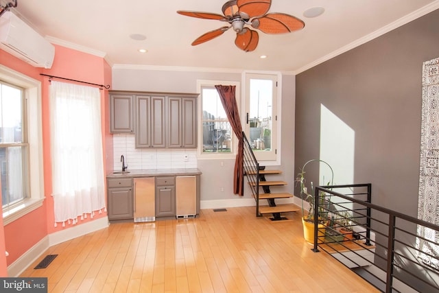 kitchen with backsplash, a wall unit AC, ornamental molding, light wood-style flooring, and a sink