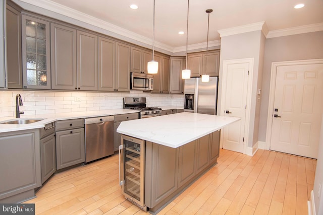 kitchen with beverage cooler, gray cabinets, ornamental molding, a sink, and appliances with stainless steel finishes